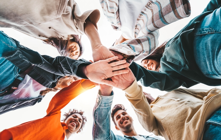 Cercle de mains photographié par en dessous avec des personnes souriantes