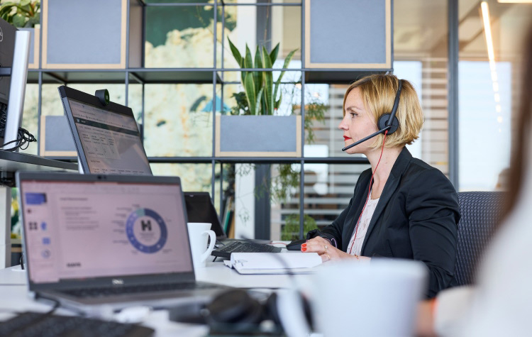 eine Mitarbeitende arbeitet mit Headset am PC