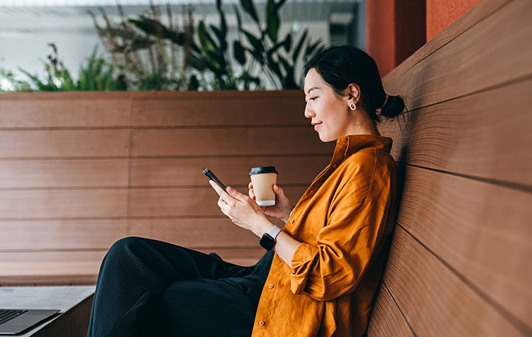 Eine Dame sitzt auf dem Sofa bedient ihr Smartphone