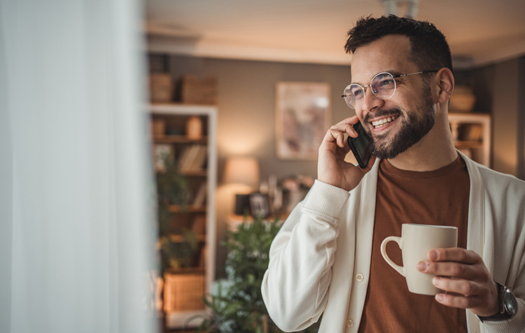 Mann am Telefon mit einer Tasse in der Hand