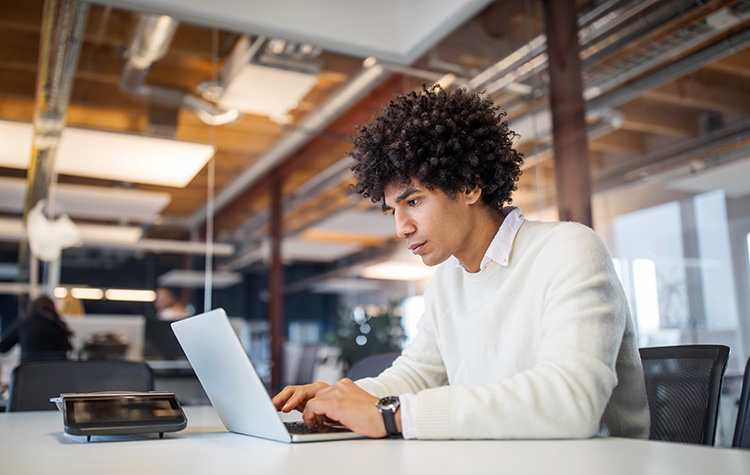 Junger Herr an einem Laptop in einem Büro