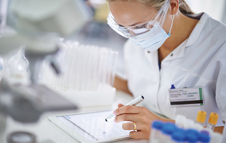 Laborantin mit einem Stift in der Hand bedient ein Tablet